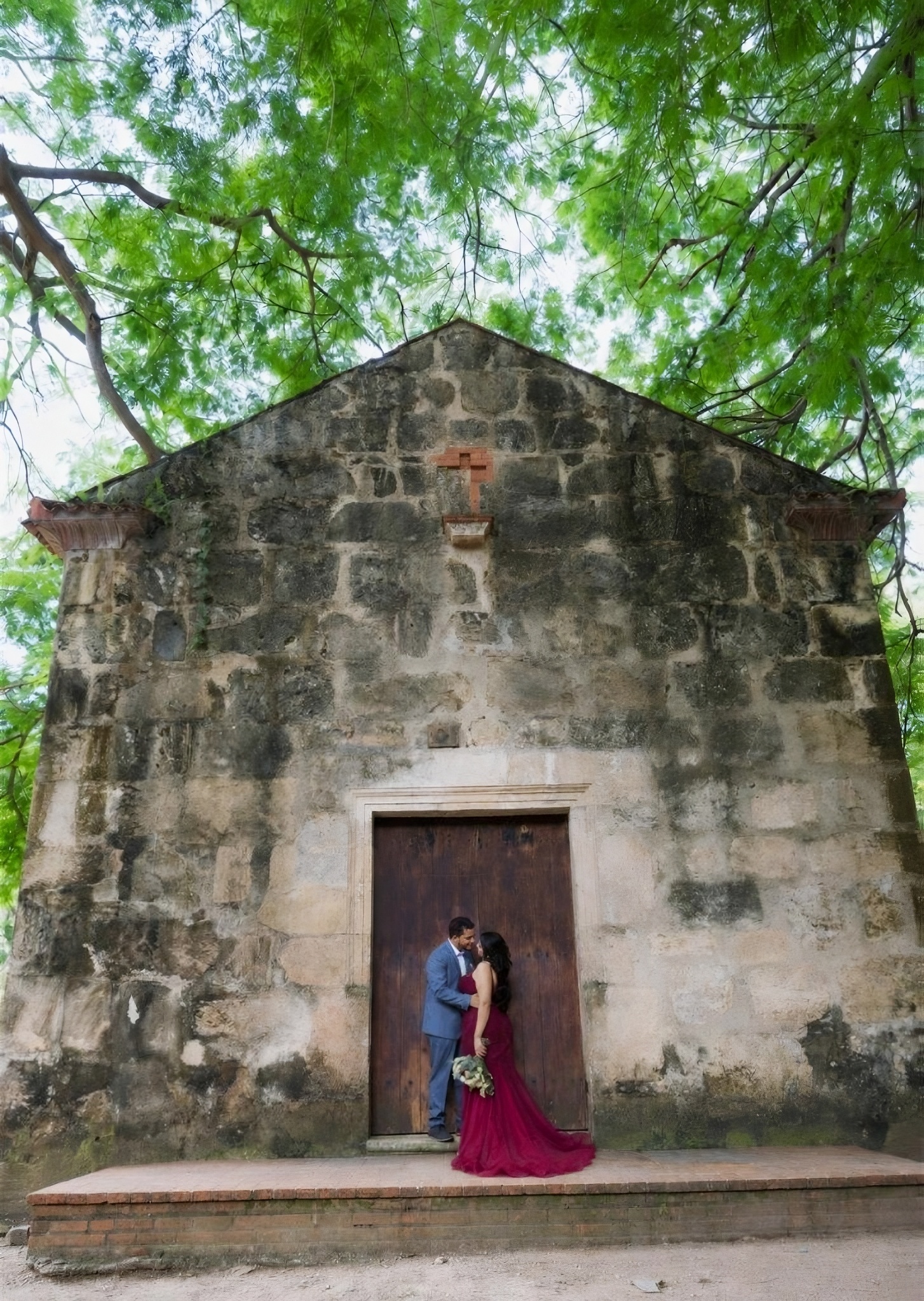 Beso frente a la capilla colonial con la cruz